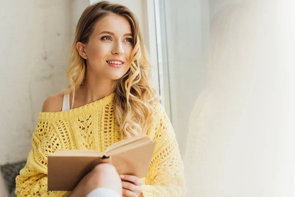 Beautiful Smiling Young Woman Holding Book While Sitting Window Sill — Stock Photo, Image