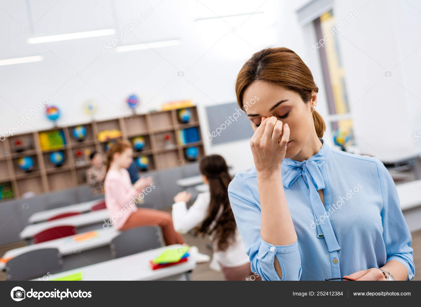 Tired Teacher Blue Blouse Standing Front Desks Touching Nose