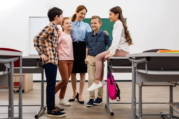 教室で黒板の前で生徒を抱きしめる笑い教師 — ストック写真