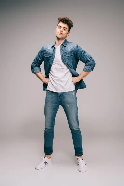 Homem Bonito Jeans Posando Com Mãos Nos Quadris Cinza — Fotografia de Stock