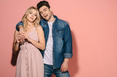 kız pembe elbisesi ve yakışıklı erkek kot gömlek sarılma ve kameraya bakıyor 