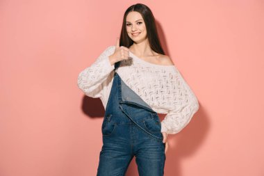 gülümseyen ve güzel bir kadın gibi gösterilen ve kameraya bakarak denim tulum içinde 
