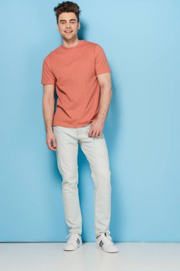 handsome and brunette man in t-shirt and jeans looking at camera  clipart