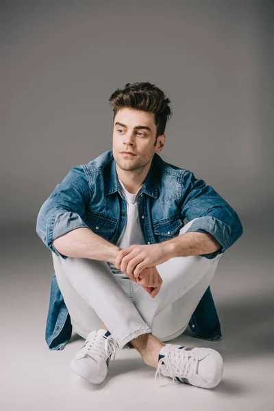 Homem Bonito Camisa Jeans Jeans Sentado Chão Olhando Para Longe — Fotografia de Stock