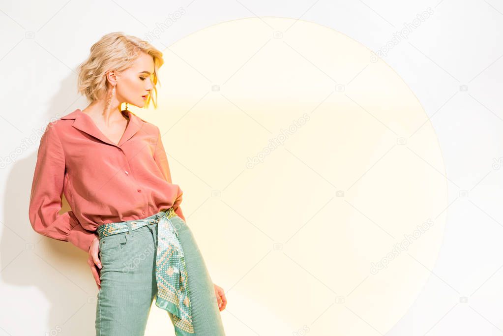 beautiful stylish girl in colorful clothes posing on white with yellow circle and copy space