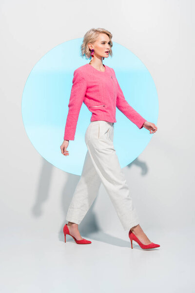 красивая модная молодая женщина позирует на белом с голубым кругом
