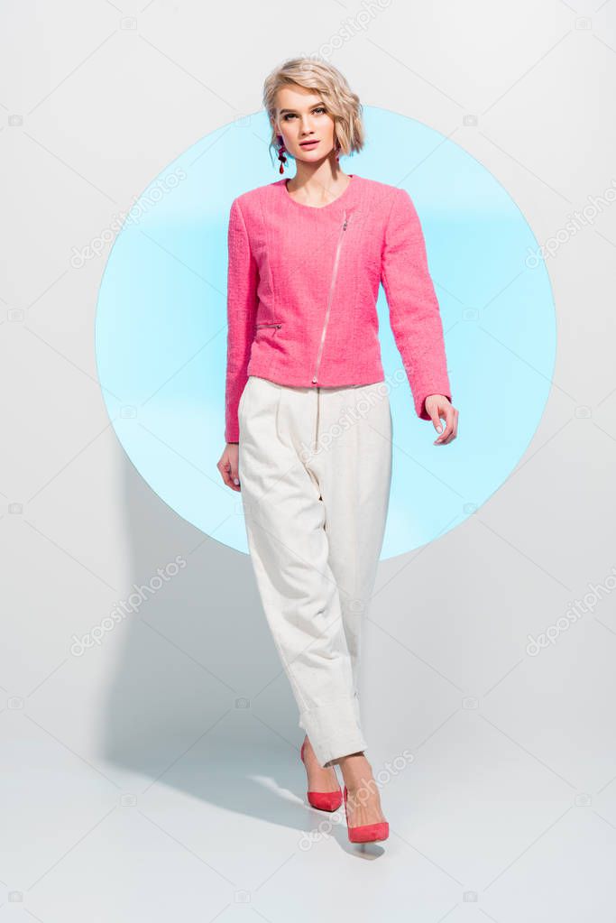 beautiful stylish girl looking at camera and posing on white with blue circle