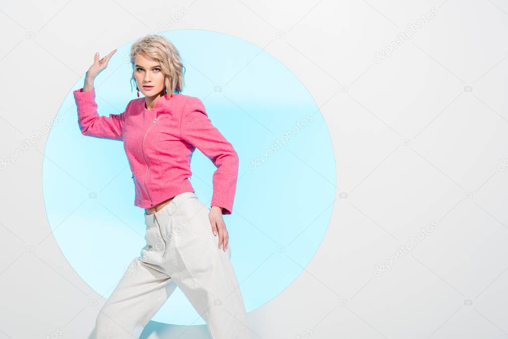 beautiful stylish girl looking at camera and posing on white with blue circle and copy space