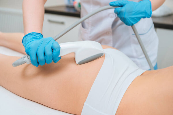 Cropped view of cosmetologist with roller doing buttocks starvac massage