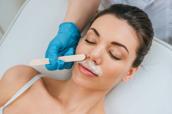 Частичное наблюдение косметолога в резиновых перчатках при щелочной депиляции
