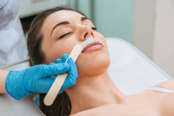 Частичное наблюдение косметолога в резиновых перчатках при щелочной депиляции
