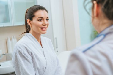 Güzellik uzmanı güzellik Kliniği bakarak beyaz bornoz güzel gülümseyen genç kadın