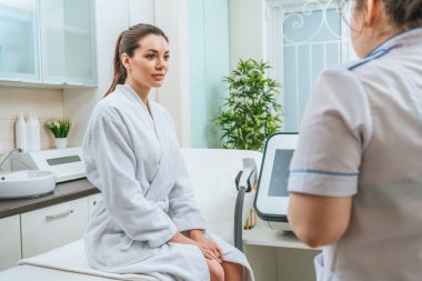 Güzellik uzmanı güzellik Kliniği bakarak beyaz bornoz güzel gülümseyen genç kadın