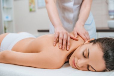 Masör kıza masaj masasında sırt masajı yapıyor kısmi görünümü