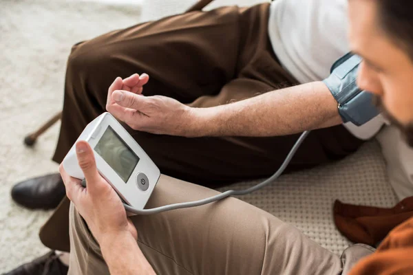 Man Holding Blood Pressure Meter While Measuring Blood Pressure Senior — Stock Photo, Image