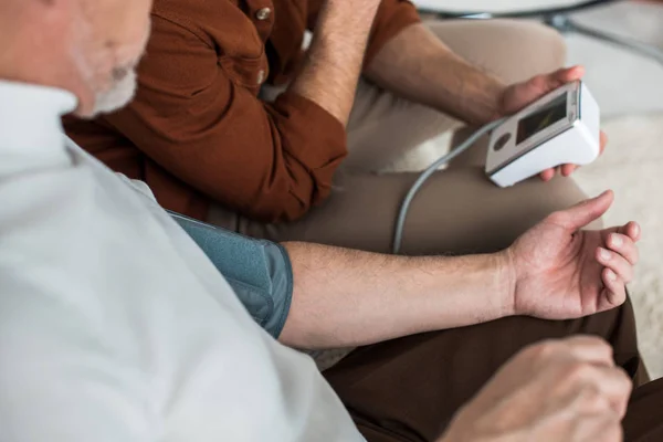 Mann Hält Blutdruckmessgerät Der Hand Während Den Blutdruck Des Älteren — Stockfoto