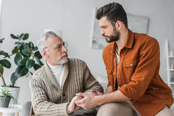 Sad Senior Father Glasses Holding Hands Handsome Son Home — Stock Photo, Image