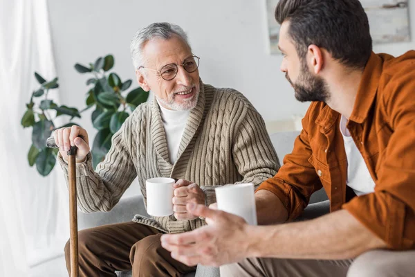 Happy Retired Father Glasses Looking Handsome Son Holding Cup — Stock Photo, Image