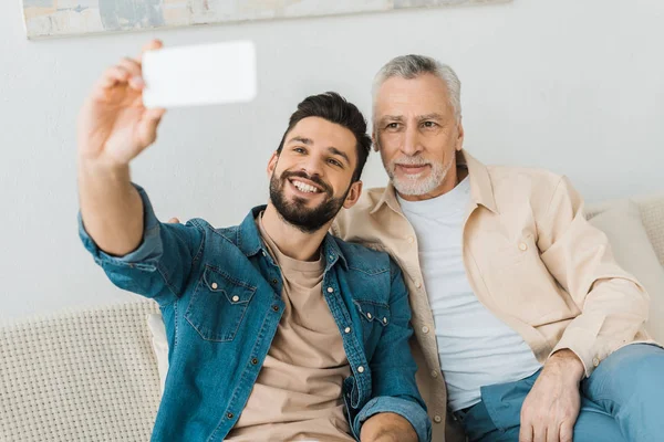 Homem Barbudo Alegre Tomando Selfie Com Pai Sênior Casa — Fotografia de Stock