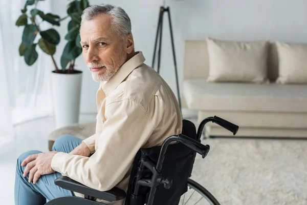 残疾退休男子坐在家里轮椅上看着相机 — 图库照片