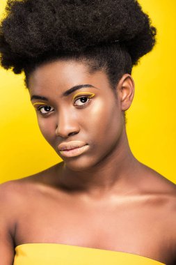 Çekici African Amerikan kadın moda makyaj görünümlü kamera izole sarı