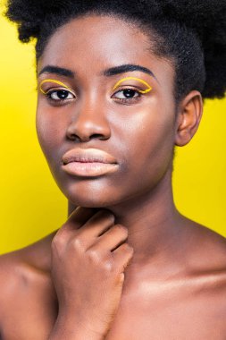 Çekici African Amerikan kadın moda makyaj görünümlü kamera izole sarı