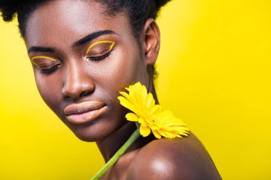 Sarı üzerinde izole çiçek tutan kapalı gözler ile Afrikalı Amerikalı kız kırpılmış görünümü