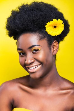 Sarı üzerinde izole çiçek ile güzel Afrikalı Amerikan kadın gülümseyen