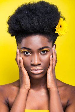 Sarı üzerinde izole kamera bakarak çiçek ile ciddi Afrikalı Amerikalı kız
