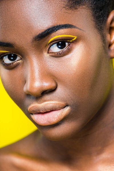 Partial view of african american woman with makeup isolated on yellow