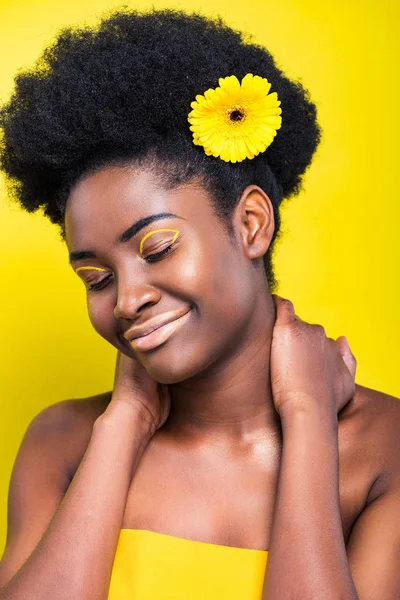 黄色に孤立した花を持つ美しいアフリカ系アメリカ人の女性を笑顔 — ストック写真