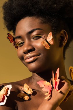 Kahverengi üzerinde izole kelebekler ile gülümseyen Afrikalı Amerikan kadın