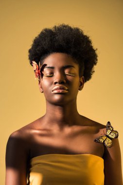 Kapalı gözleri kahverengi üzerinde izole kelebekler ile rahat Afrikalı Amerikalı kadın