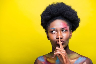 Sarı üzerinde sessiz jest gösteren parlak makyaj ile Afrikalı Amerikalı kadın