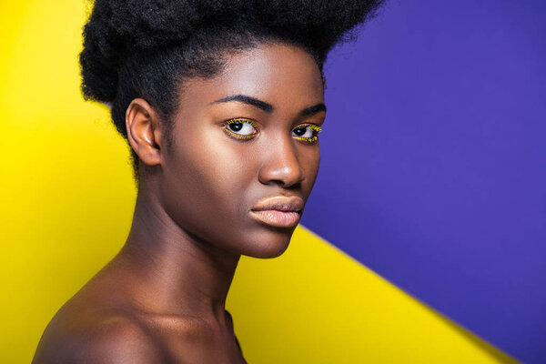 Serious african american woman looking at camera on yellow and purple