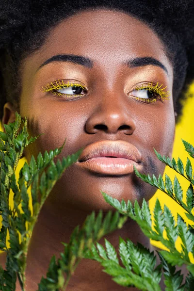 緑のシダが黄色に分離された美しいアフリカ系アメリカ人の少女 — ストック写真