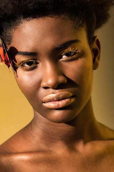 Gorgeous african american woman with butterfly looking at camera on brown