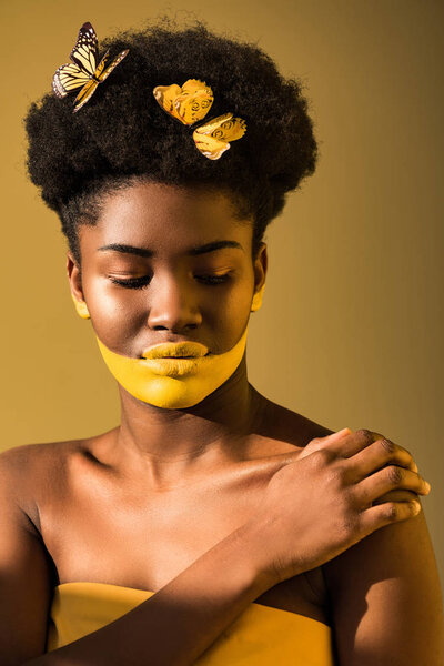 Charming african american woman with butterflies and yellow body art on brown