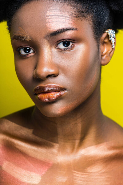 Pensive attractive african american woman with ear cuff on yellow