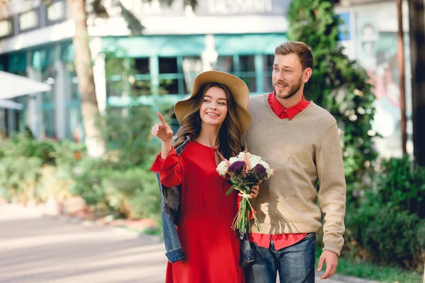 Homem Feliz Com Namorada Atraente Chapéu Segurando Flores Apontando Com — Fotografia de Stock