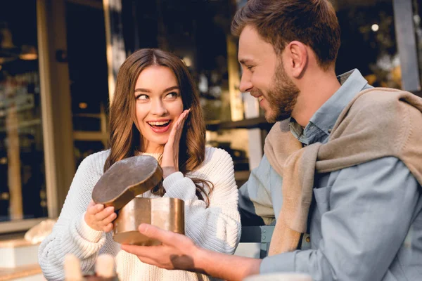 Überraschte Frau Schaut Freund Mit Herzförmiger Schachtel — Stockfoto