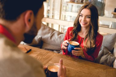 kahve fincan tutarak adam bakarak neşeli genç kadının seçici odak 