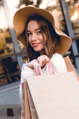 alışveriş çantaları tutarken gülümsemek neşeli genç kadın şapka 