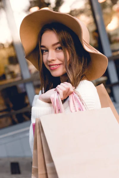 Alegre Joven Mujer Sombrero Sonriendo Mientras Sostiene Bolsas Compras —  Fotos de Stock