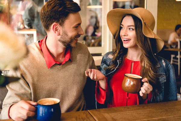 Счастливая Молодая Женщина Шляпе Смотрит Мужчину Держа Чашку Кофе — стоковое фото