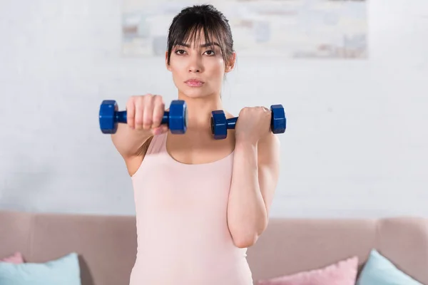 Attractive young woman doing exercise with dumbbells at home — Stock Photo