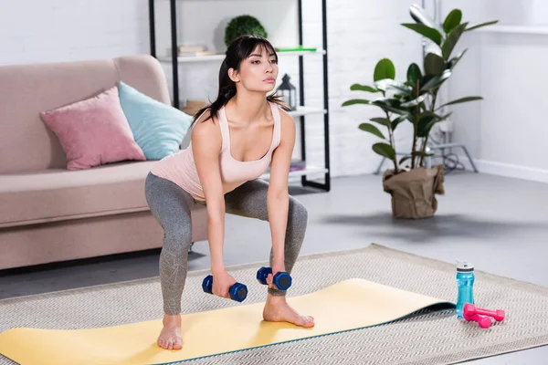 Giovane donna sportiva che fa squat con manubri a casa — Foto stock