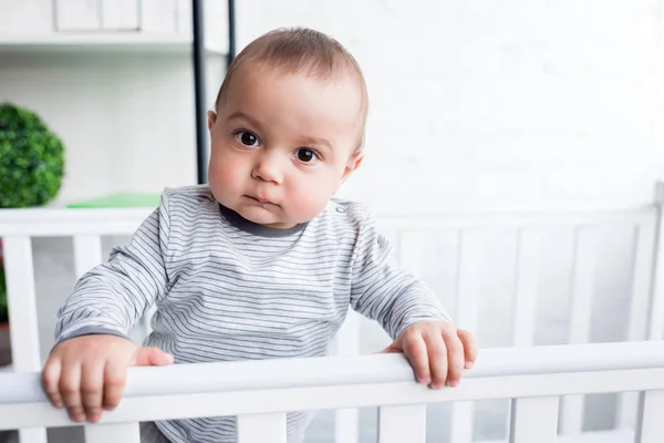 Nahaufnahme Porträt eines entzückenden Kindes im Babybett, das in die Kamera blickt — Stockfoto