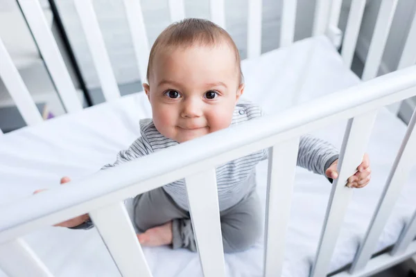 High angle view of adorable little child sitting in baby cot — Stock Photo