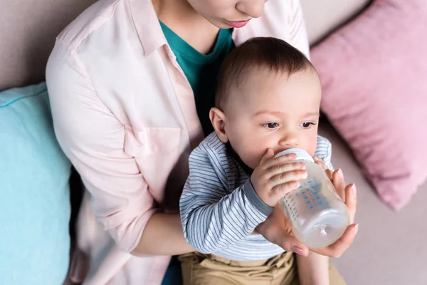 Corte tiro de mãe alimentando seu filho com garrafa em casa — Fotografia de Stock